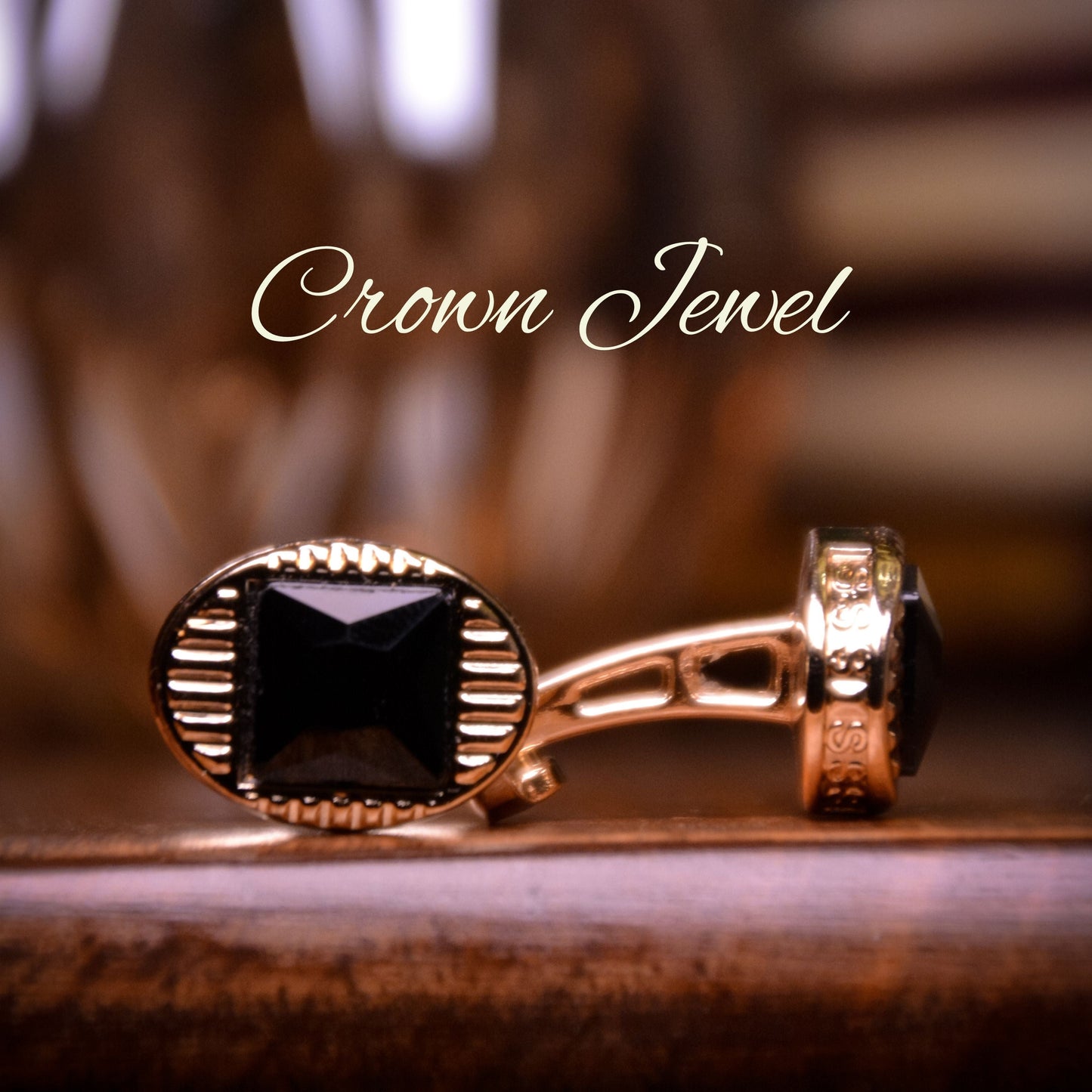 Gold cufflinks with black gemstones on a wooden surface, branded 'Crown Jewel'.