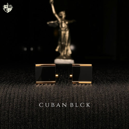 A pair of men's cufflinks with rectangular black enamel faces and gold-toned edges, displayed on a dark textured surface with a blurred gold statue in the background. The text 'CUBAN BLACK' is visible at the bottom.